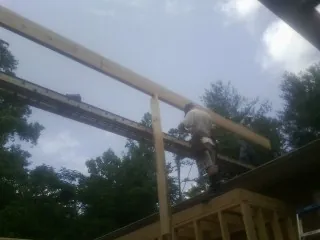 Carpenter setting a ridge beam over a new addition frame — Ice Dam Removal by Roofing Brothers in Omro