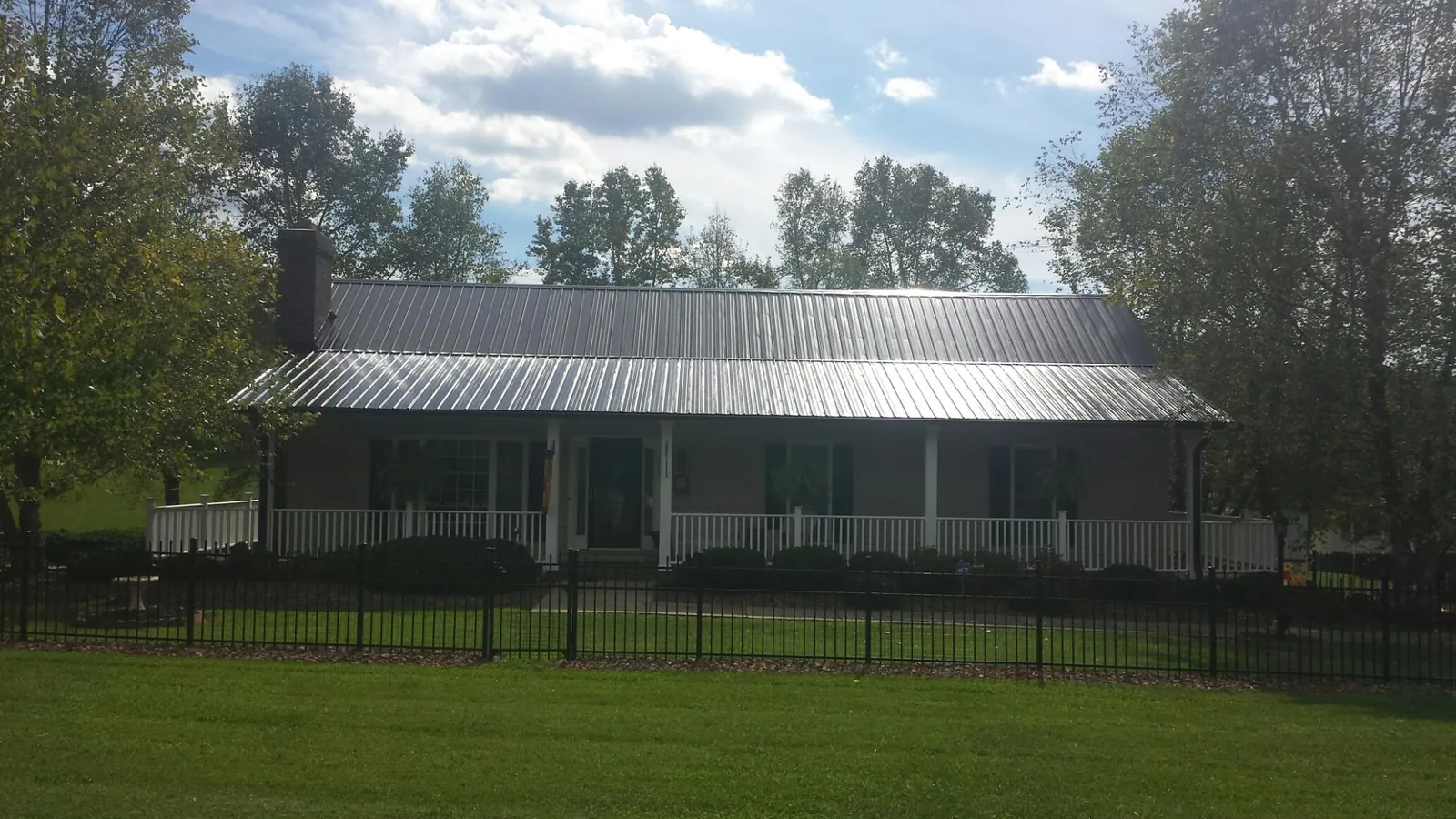 Gray metal roof on a brick ranch with a full width front porch — Gutter Guard Installation work by our crew in Omro