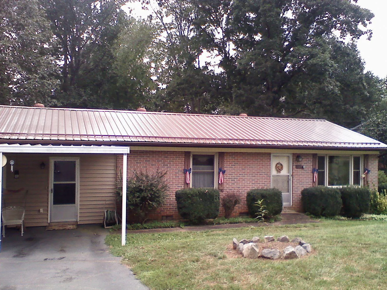 Bronze metal roof and carport on a brick ranch home — Roof Repair work by our crew in Omro
