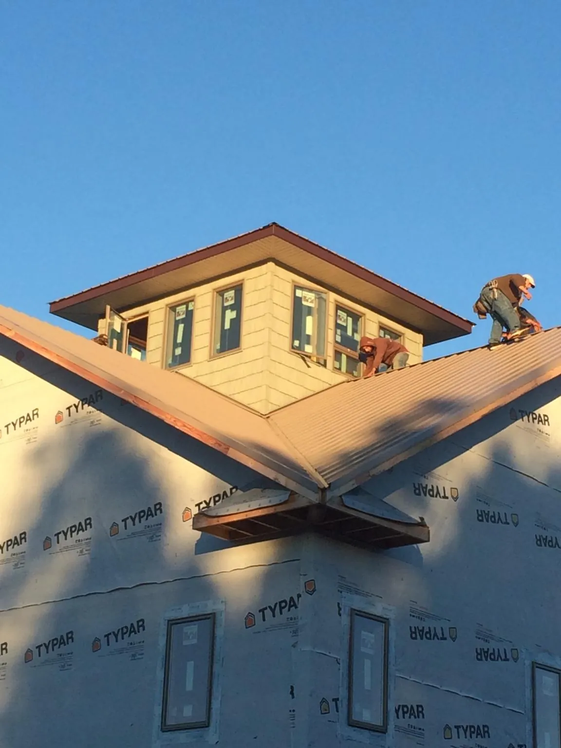 Roofers working around a rooftop cupola on a new metal roof at sunset — Roof Waterproofing in Omro by Roofing Brothers